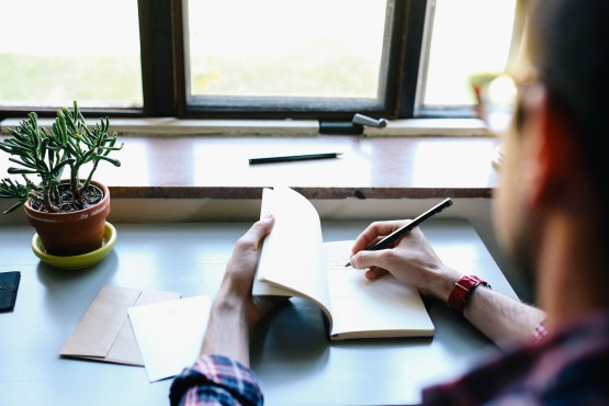 man writing in journal